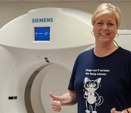 Wendy giving a thumbs up while standing in front of a CT scanner